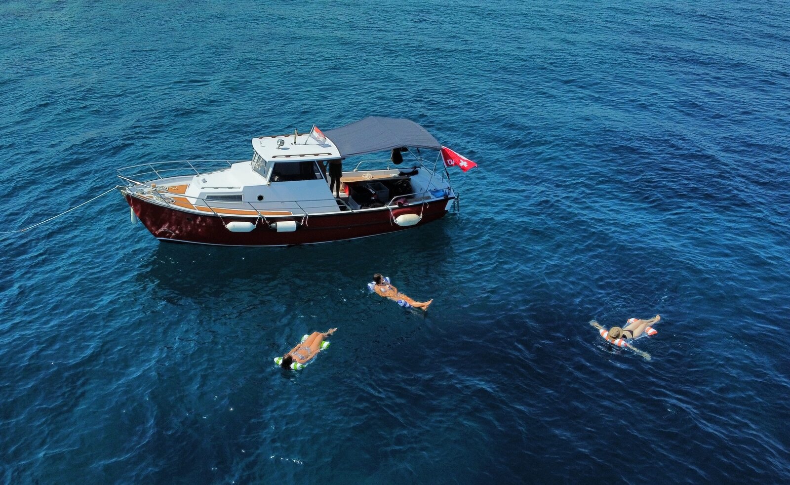 A single wooden boat anchored in a quiet, crystal-clear Adriatic bay