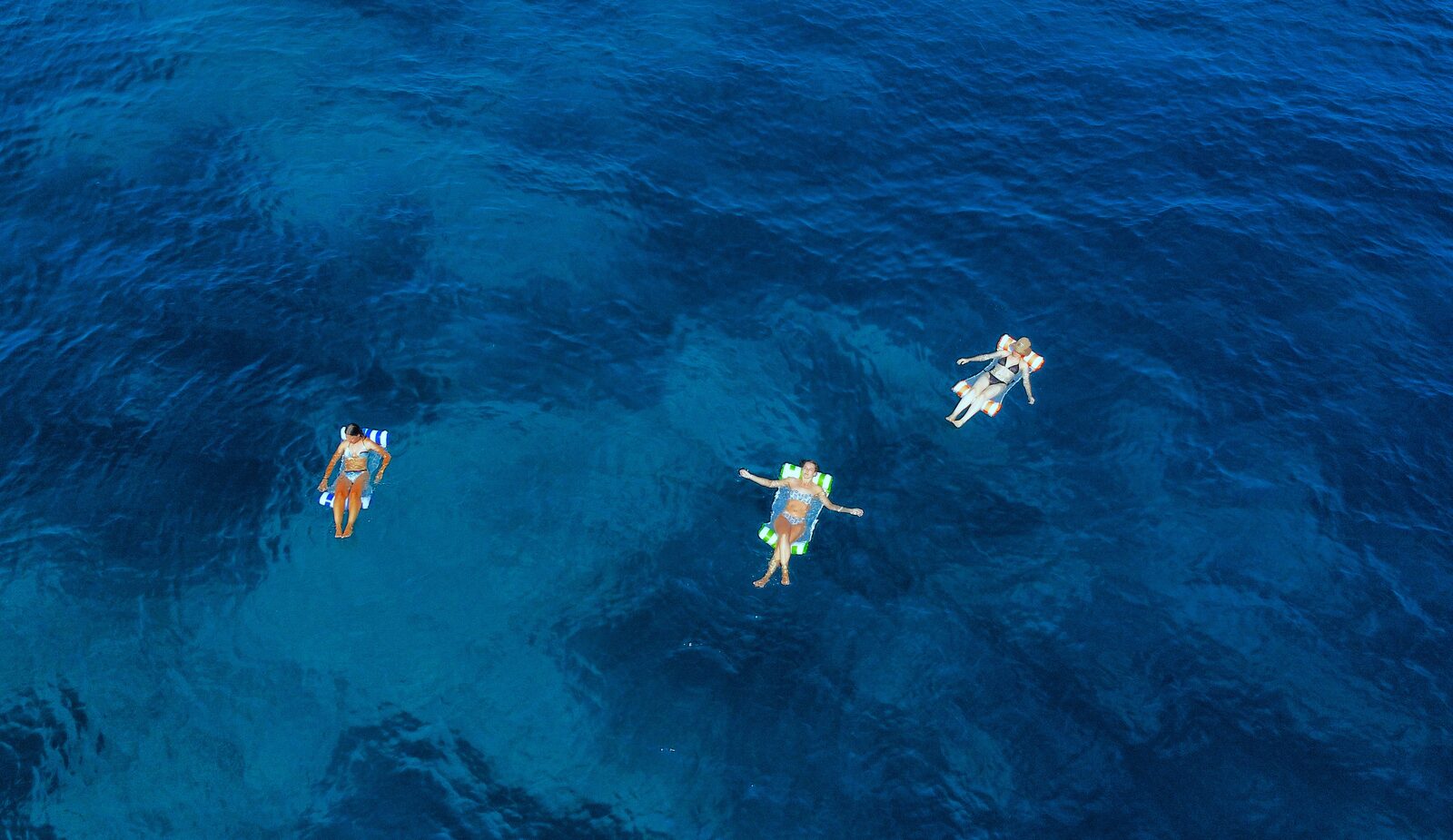 Group of people swimming and floating in clear Adriatic water next to a boat